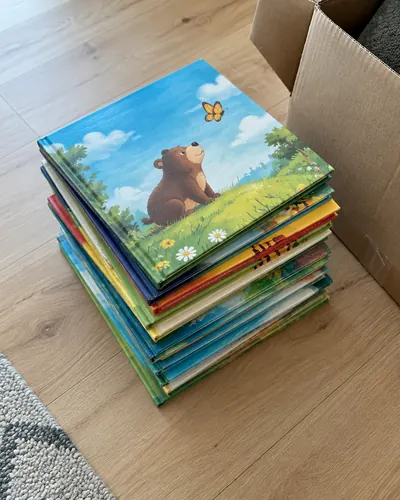 Stapel kleurrijke prentenboeken naast een verhuisdoos