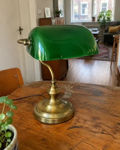 Vintage bureaulamp met groene glazen kap op een houten tafel