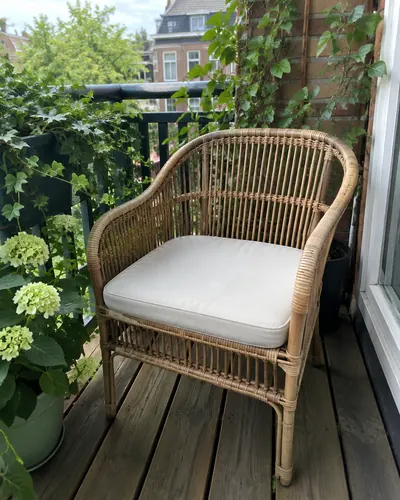 Rotan fauteuil met crème kussen op een houten balkon